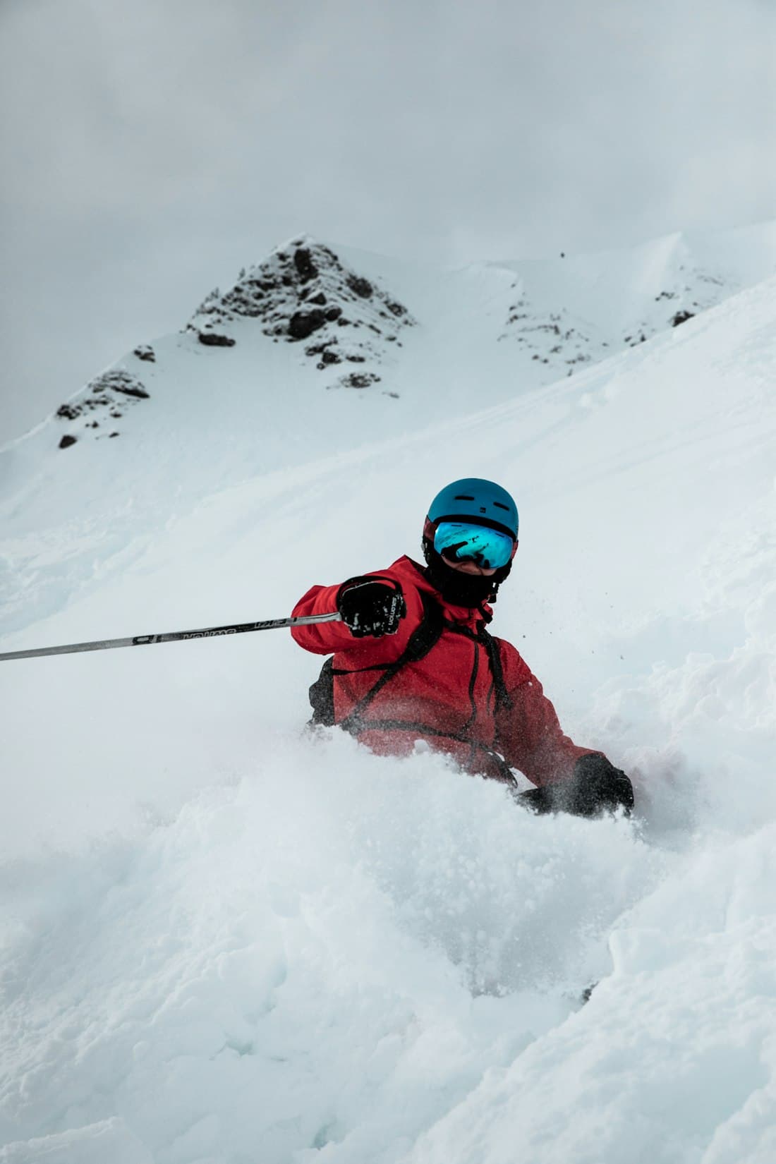 A skier in a red jacket carving through deep powder snow