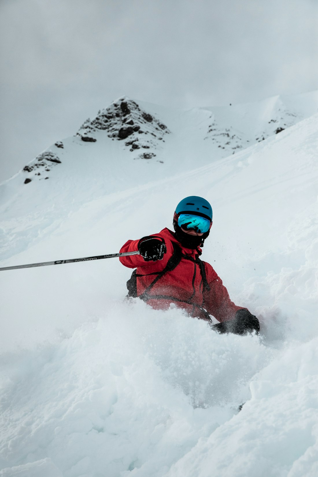 A skier in a red jacket carving through deep powder snow